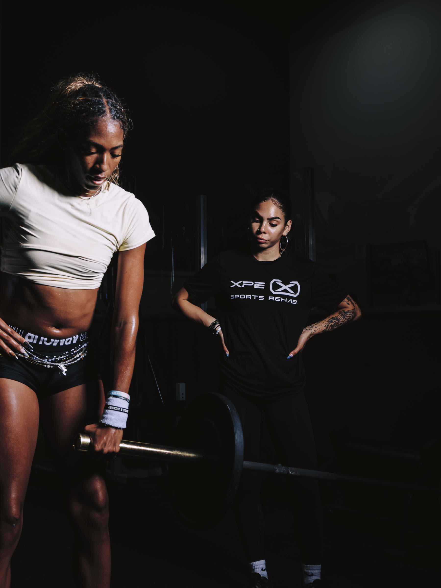 Nicole watching an athlete set up for a deadlift.